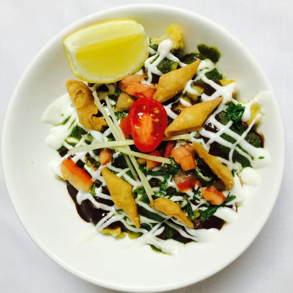 Indian chaat with yogurt, green chutney, tamarind sauce, tomatoes, and crispy fried dough.