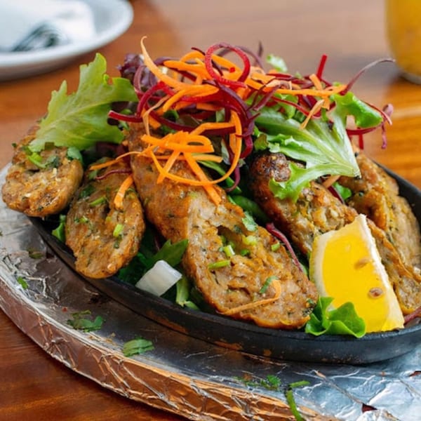 Indian seekh kebabs with fresh salad and a lemon wedge, served on a sizzling platter.